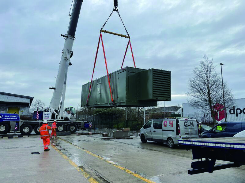 A crane positioning a containerized energy storage system at the German reference site.